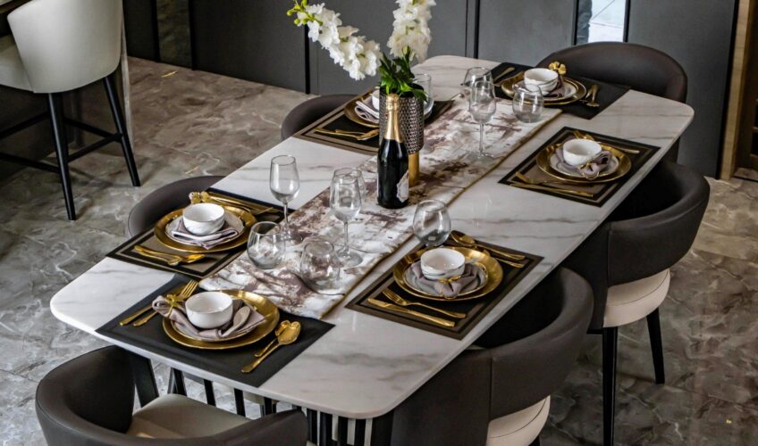Fine dining set up with full cutlery glassware and charger plate on a marble table